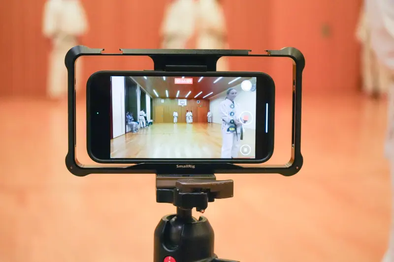 Smartphone auf Stativ filmt zwei Personen bei einer Kata