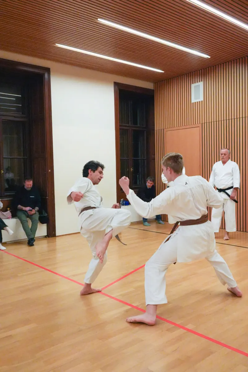 Zwei Personen üben Kumite, eine führt einen Tritt aus