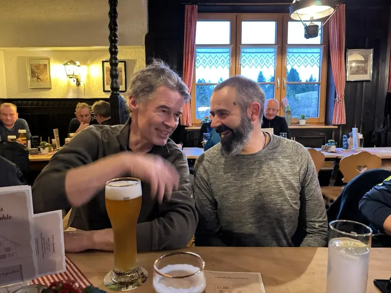 Zwei Personen sitzen lachend am Tisch in einer Gaststube