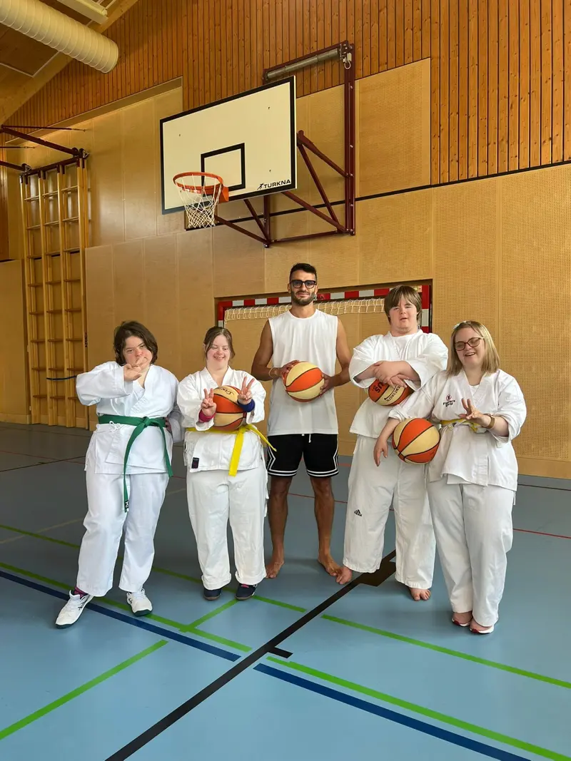 Fünf Personen im Karategi posieren mit Basketbällen in Turnhalle