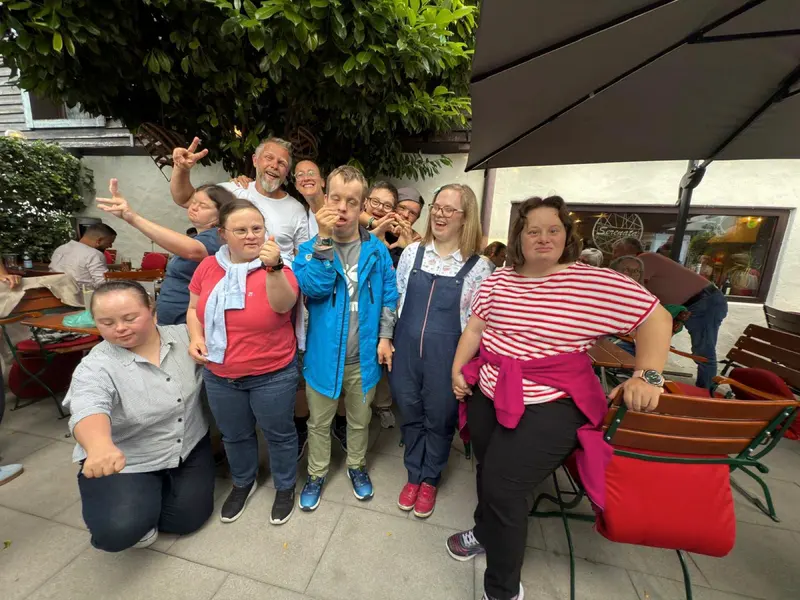Gruppe steht und kniet lächelnd zusammen auf Terrasse