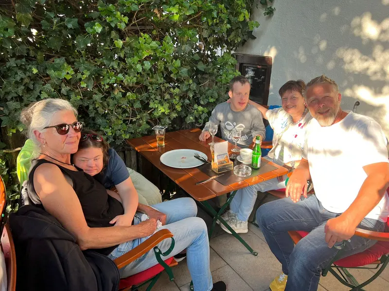 Gruppe sitzt zusammen an Tisch im Gastgarten