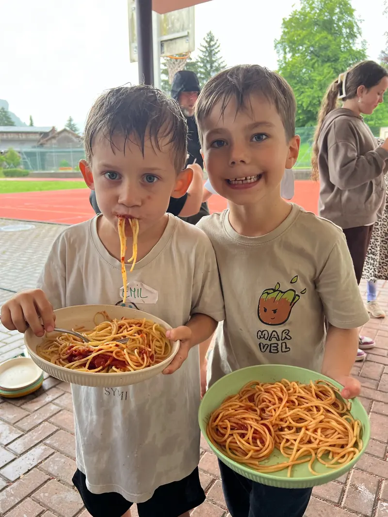 Zwei Kinder essen lächelnd Spaghetti aus Schüsseln