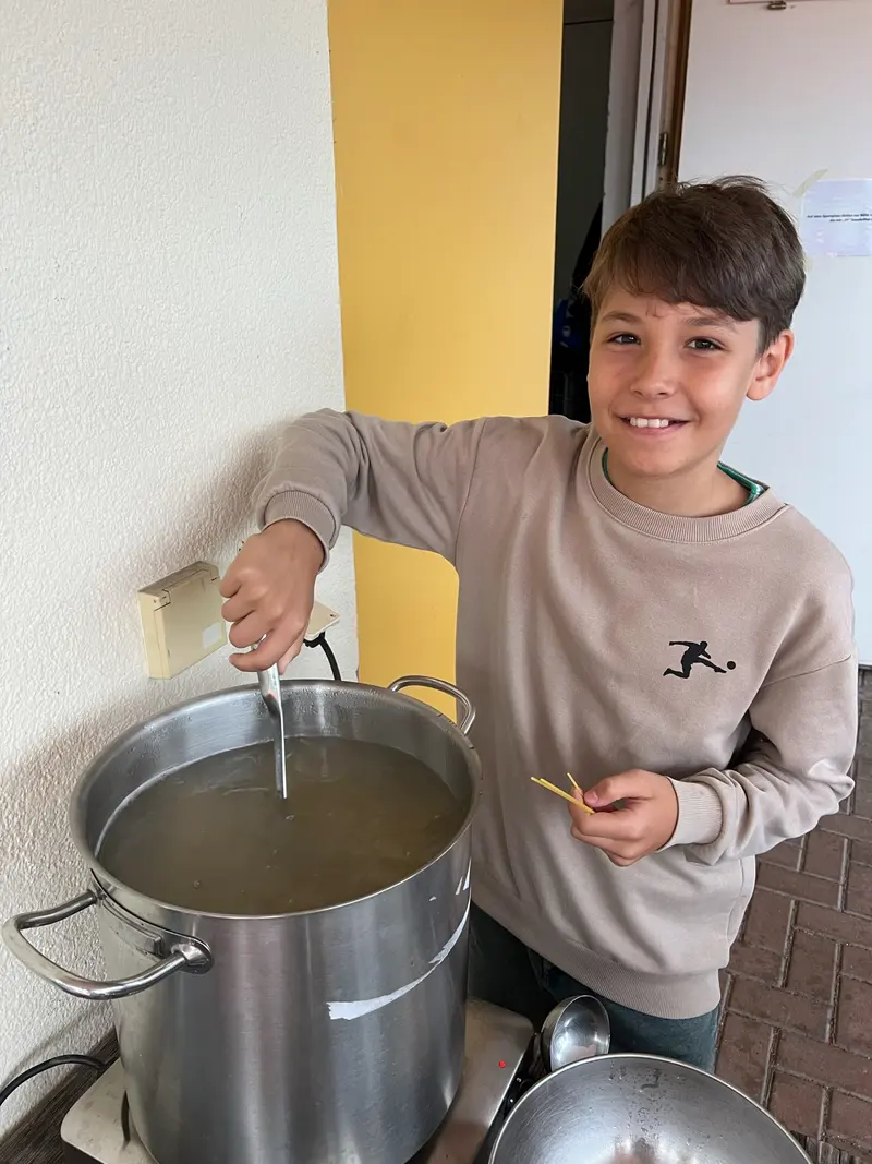 Kind rührt mit einem Kochlöffel in einem großen Topf