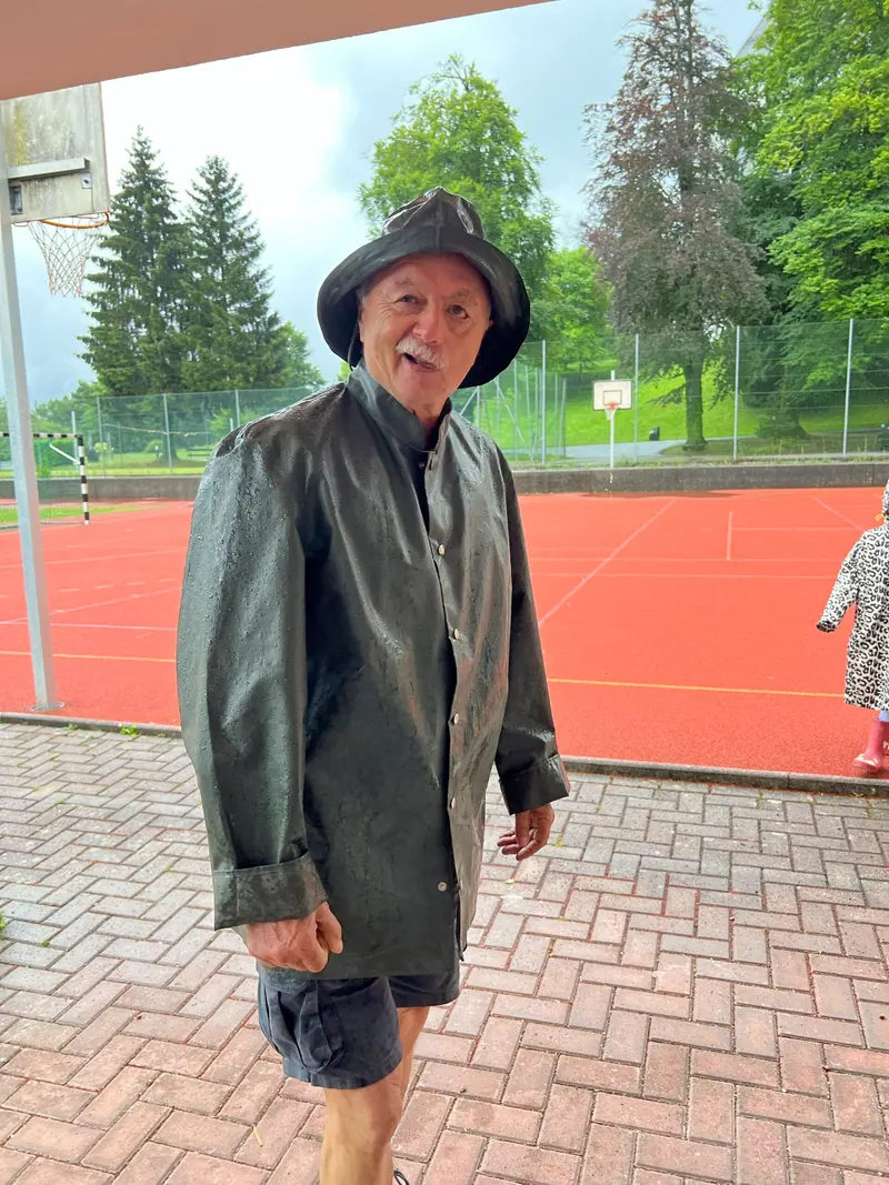 Betreuer in Regenmantel und Hut steht auf dem Sportplatz