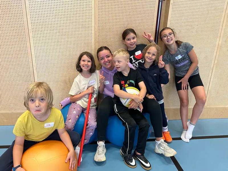 Gruppe von Kindern und Betreuern sitzt auf großen Gymnastikbällen