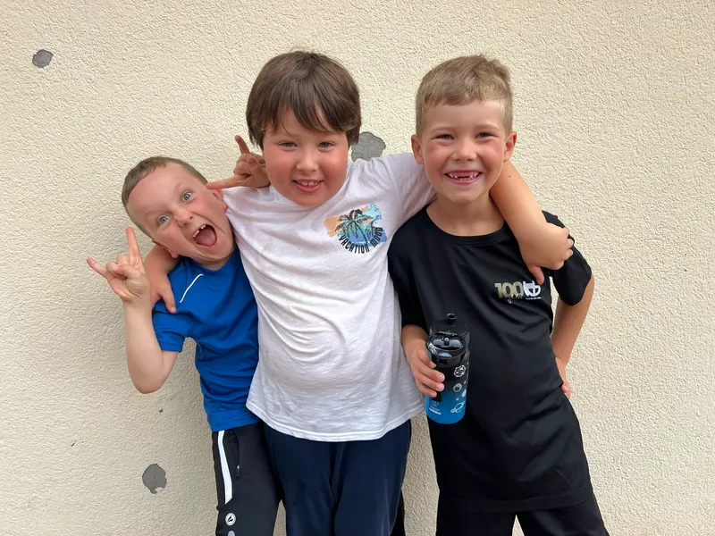 Drei Kinder posieren Arm in Arm mit Grimasse