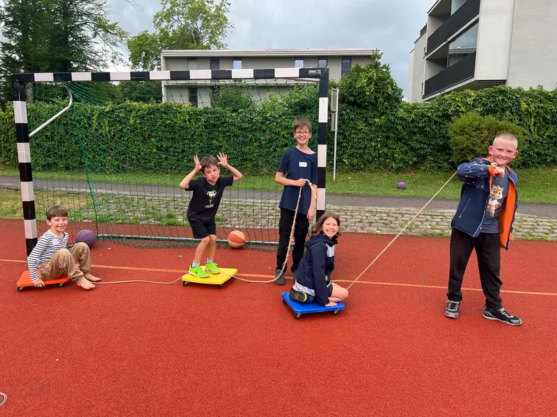 Kinder mit Rollbrettern posieren lachend auf dem Sportplatz