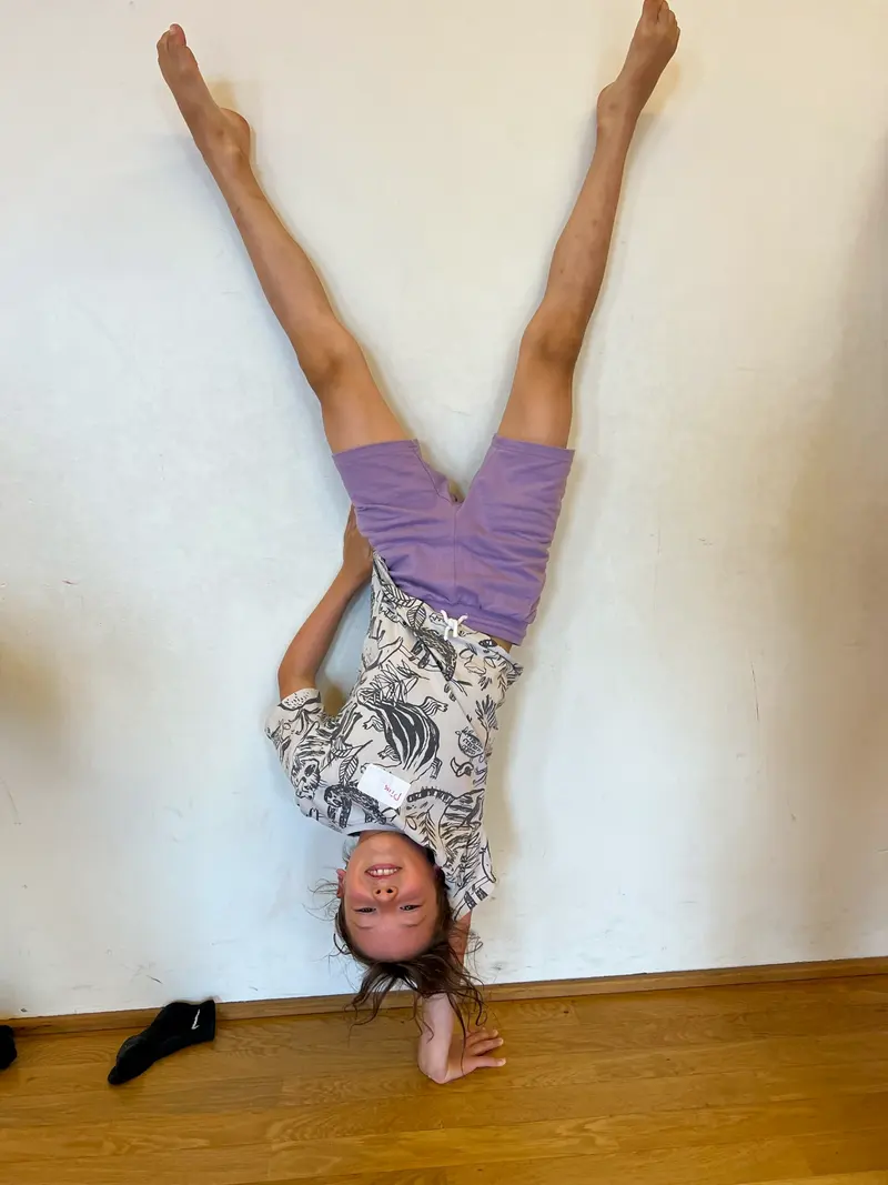 Kind macht einen Handstand an der Wand