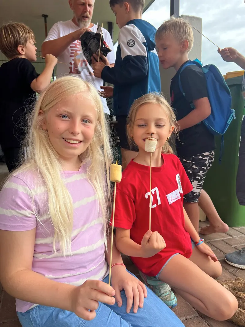 Zwei Kinder essen lächelnd Marshmallows vom Holzstab