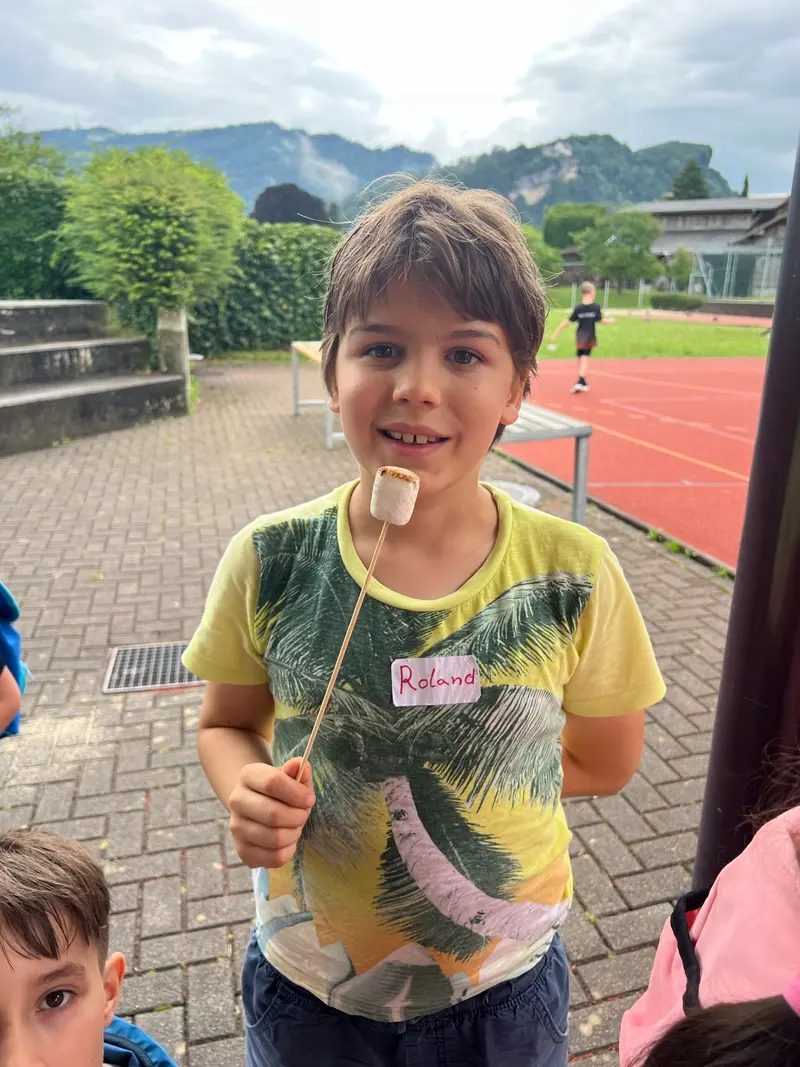 Kind isst lächelnd einen Marshmallow vom Stock