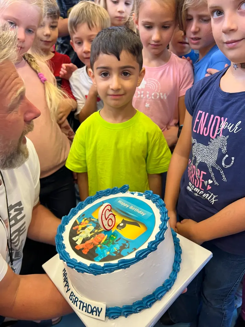 Kinder stehen um eine runde Torte herum