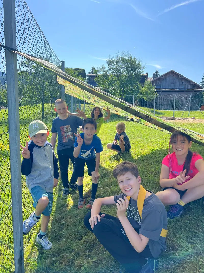 Gruppe von Kindern sitzt und steht auf einer Wiese im Freien