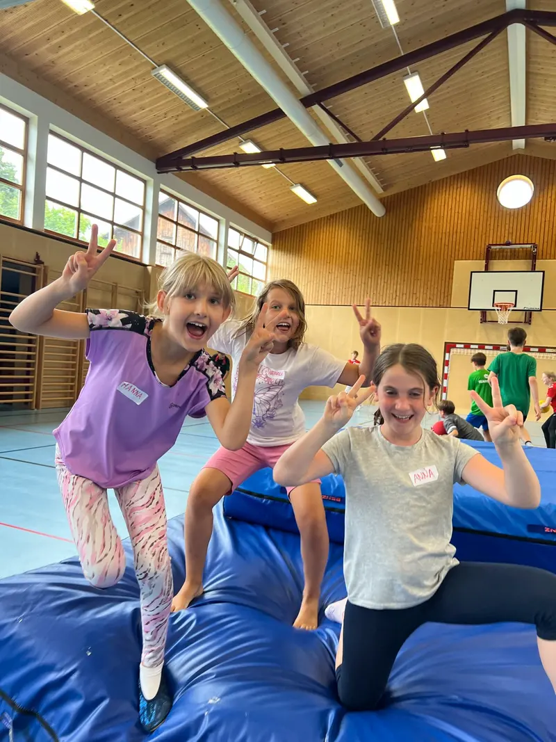 Gruppe von Kindern posiert winkend in der Turnhalle