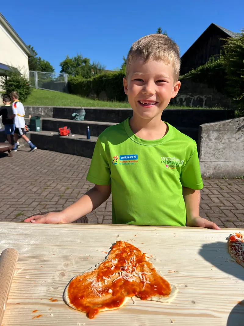 Kind lehnt lächelnd an einem Tisch im Freien
