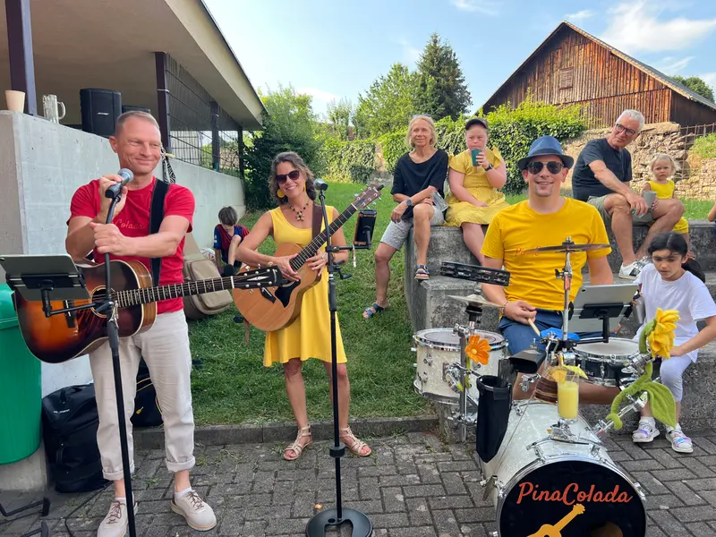 Musikband spielt mit Gitarren und Schlagzeug im Garten.
