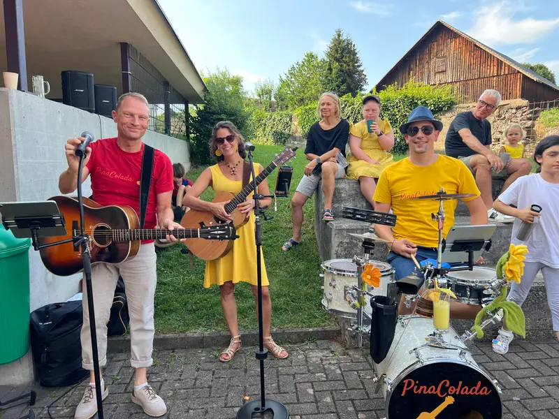 Musikband spielt mit Gitarren und Schlagzeug im Freien.