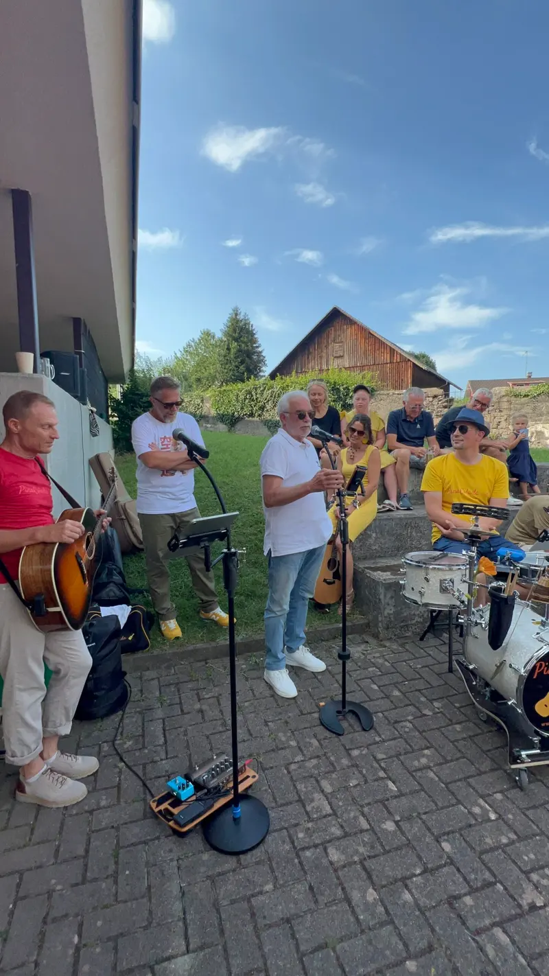 Musiker mit Gitarre und Mikrofon spielen vor Publikum.
