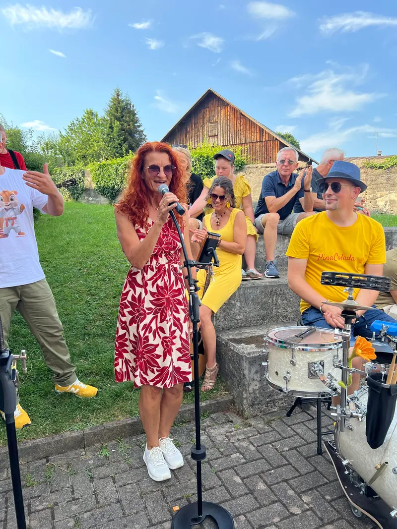 Person mit rotem Haar singt am Mikrofon vor Publikum.