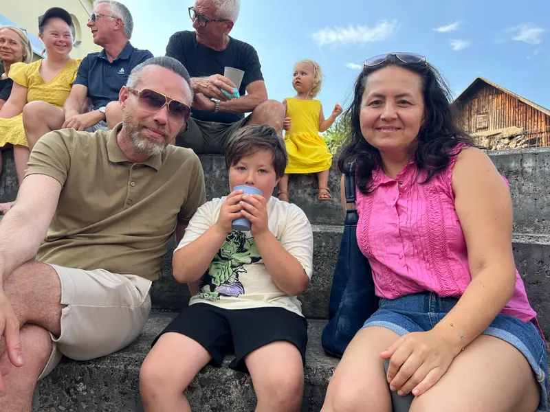 Gruppe sitzt gemeinsam auf einer Mauer im Freien.