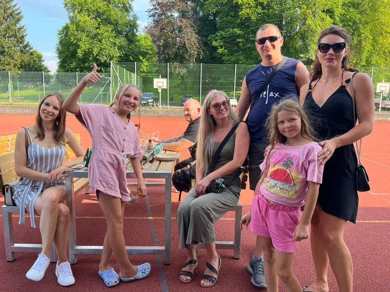 Gruppe steht und sitzt gemeinsam auf einem Sportplatz.