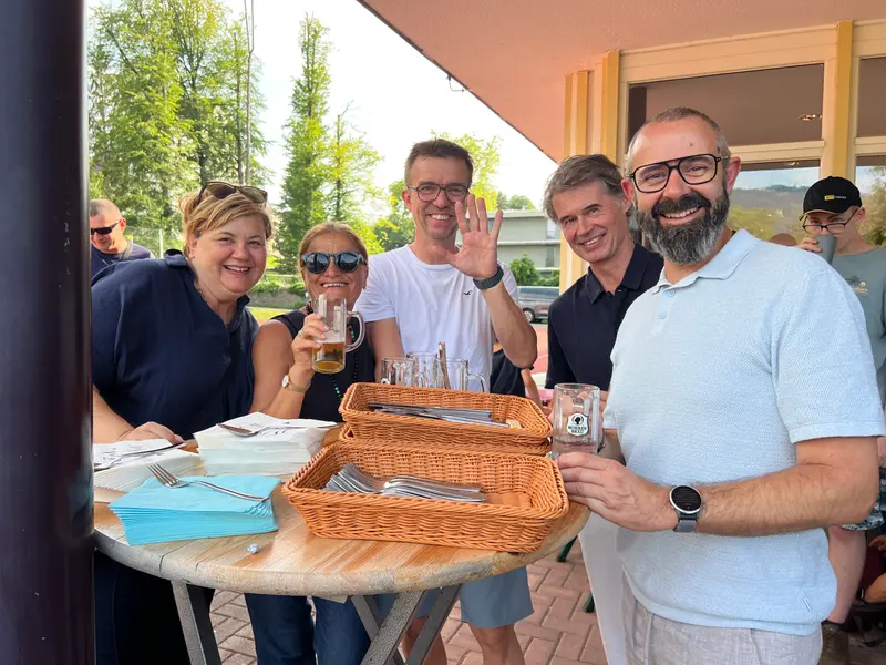 Gruppe steht mit Getränken an einem Stehtisch.