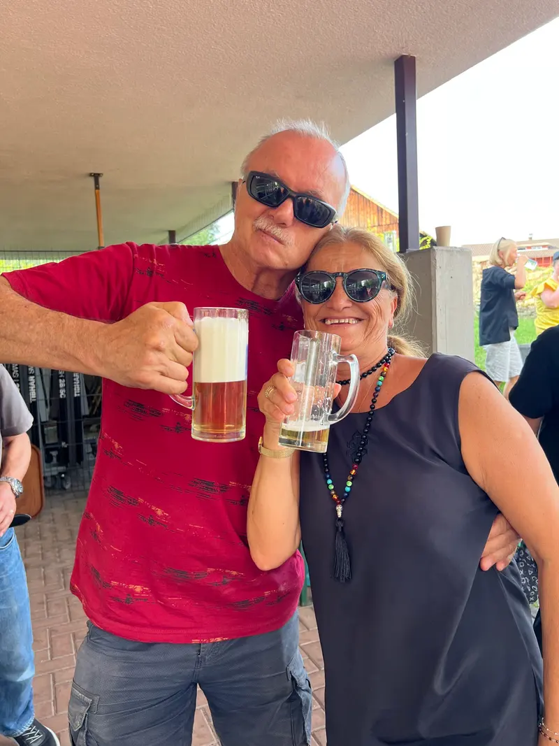 Zwei Personen stoßen lächelnd mit Biergläsern an.
