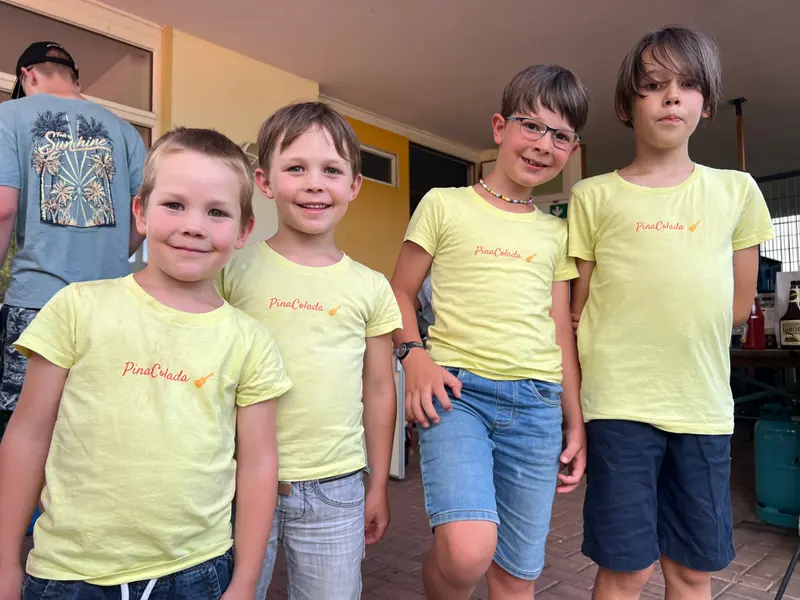 Vier Kinder in gelben T-Shirts stehen nebeneinander.