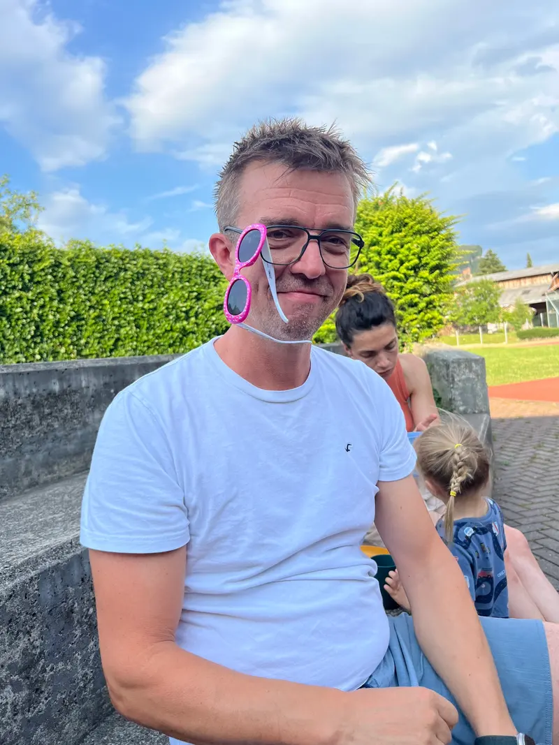 Person mit Sonnenbrille auf der Stirn lächelt in die Kamera.