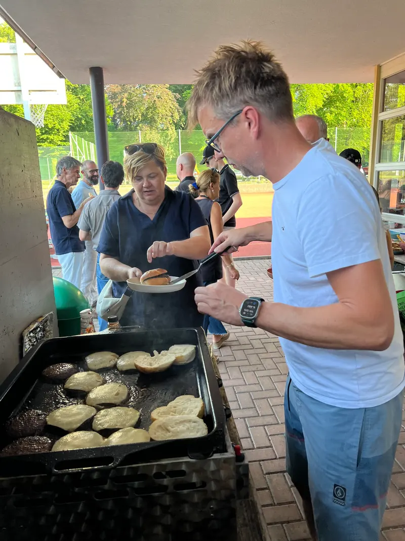 Zwei Personen stehen an einem Grill mit Fladenbroten.