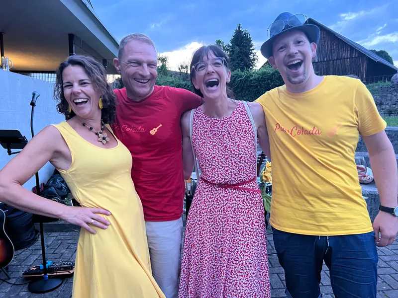 Vier Personen lachen ausgelassen zusammen im Freien.