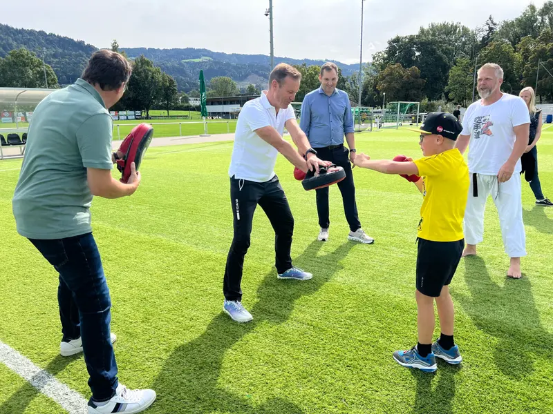 Trainer hält Schlagpolster, Kind im gelben Trikot schlägt zu