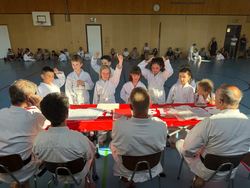 Gruppe hebt die Hand, Prüfer sitzen am Tisch