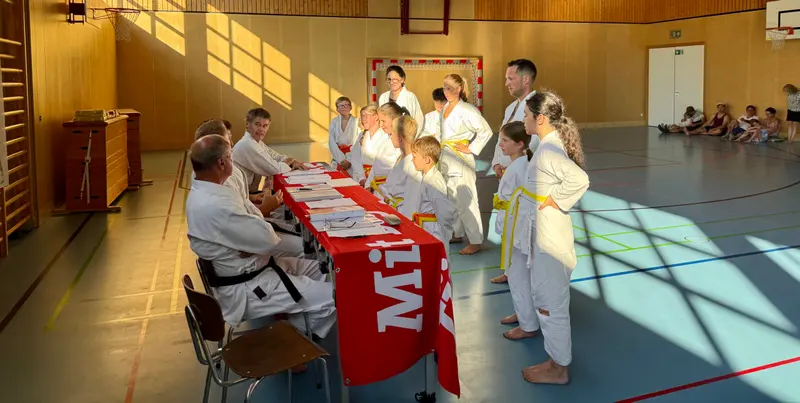 Gruppe steht vor dem Prüfertisch mit rotem Banner