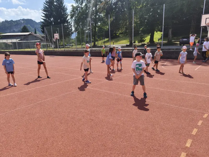 Kinder stehen mit Abstand auf dem Sportplatz