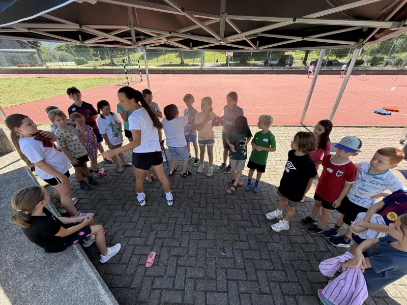 Kinder hören Betreuerin unter Pavillon im Freien zu