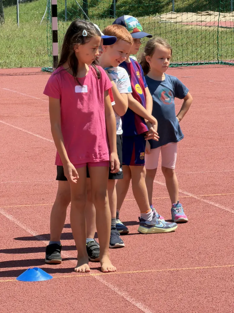 Kinder stehen in einer Reihe auf der Laufbahn