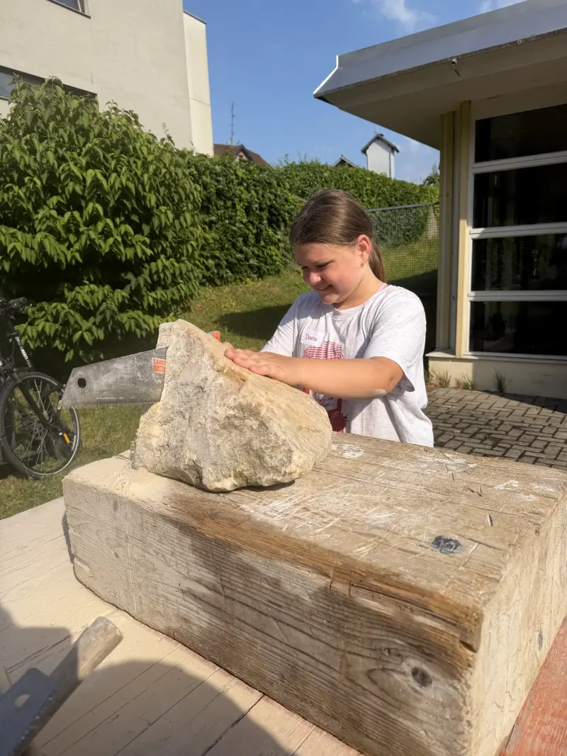 Kind sägt an einem großen Stein