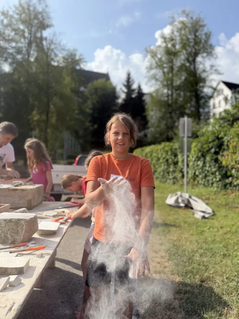 Kind klatscht Steinstaub von den Händen
