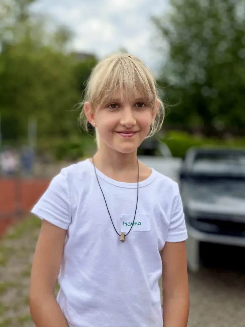 Kind trägt Steinanhänger an Kordel im Freien