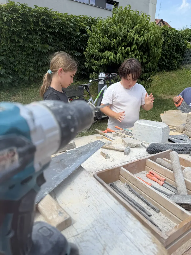Kinder bearbeiten Steinblöcke mit Meißel und Hammer