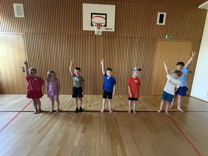 Kinder strecken in der Sporthalle die Hand hoch