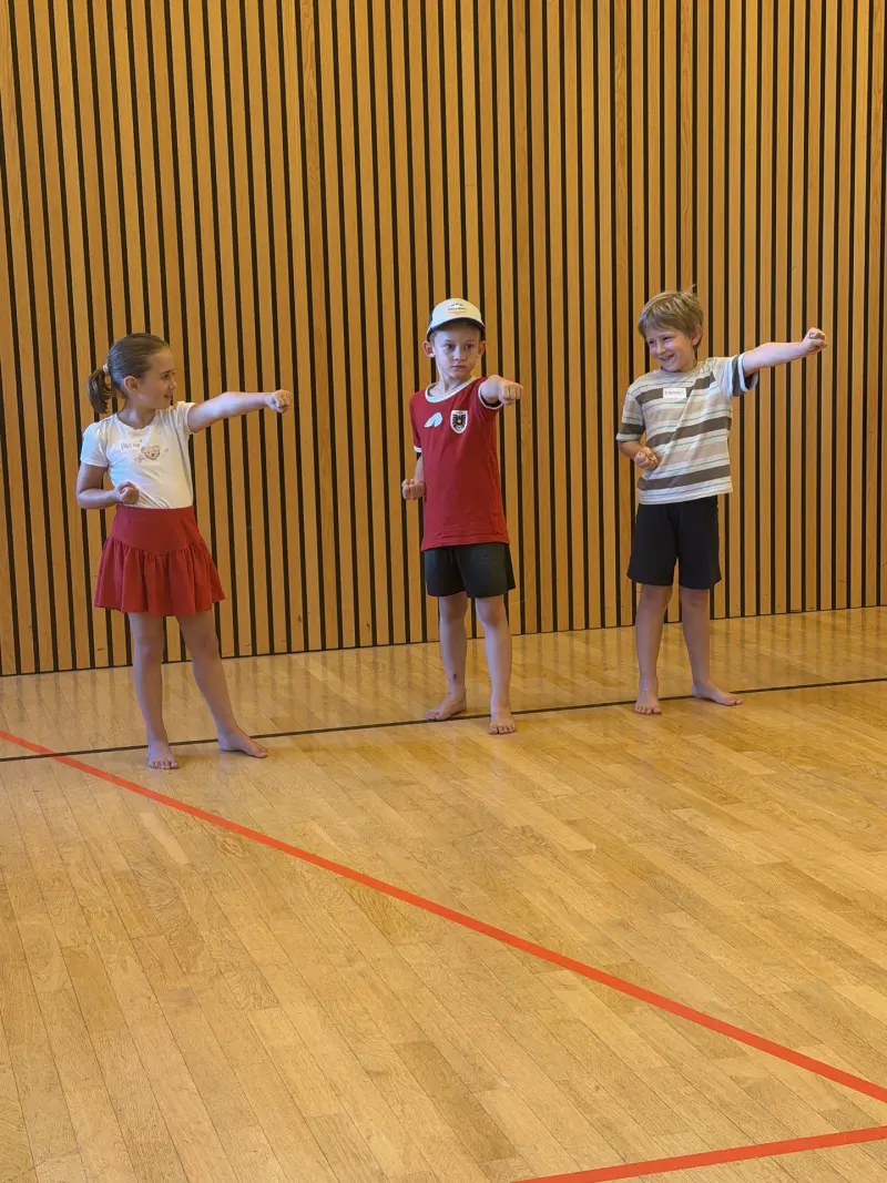 Drei Kinder üben Fauststoß in der Sporthalle