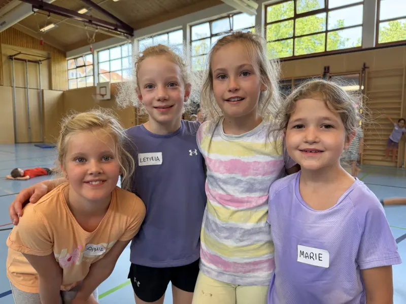 Vier Kinder posieren gemeinsam in der Sporthalle