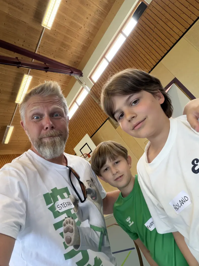 Mann macht Selfie mit zwei Kindern in Sporthalle