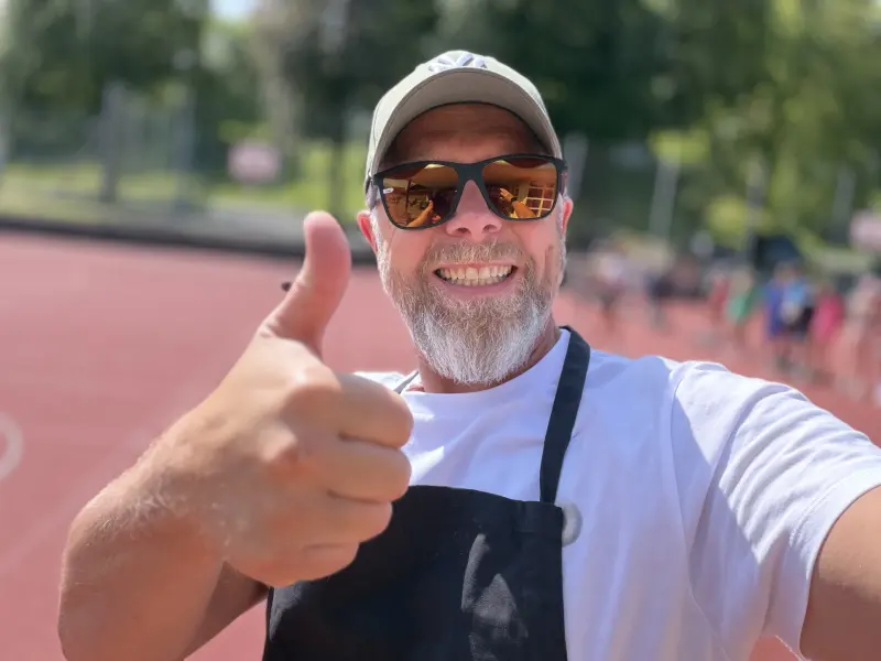 Mann mit Schürze zeigt lachend den Daumen hoch