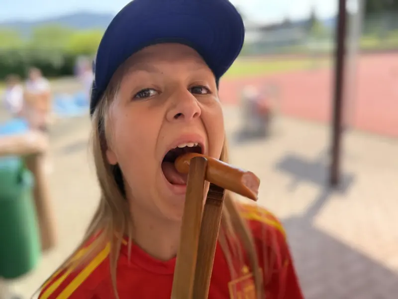 Person hält einen Holzstab zwischen den Zähnen