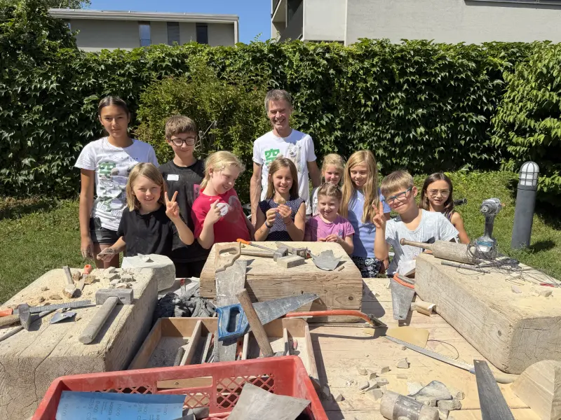 Gruppe posiert hinter Werkbänken mit Specksteinen