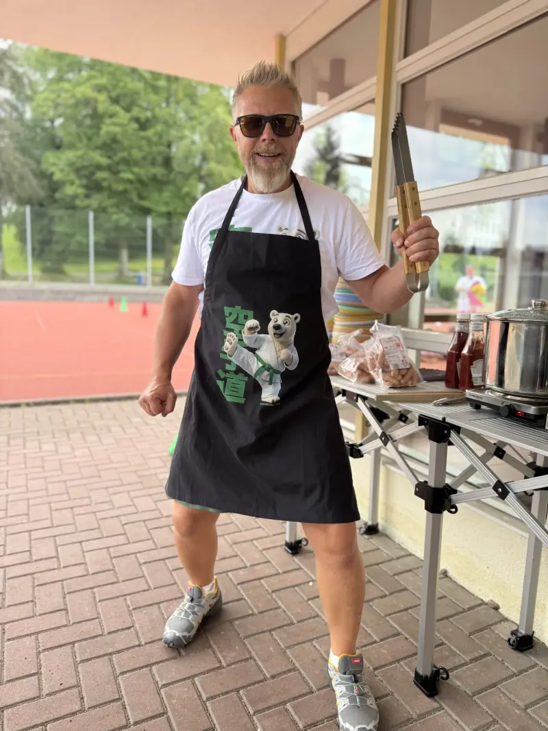 Mann grillt im Freien mit Karate-Schürze