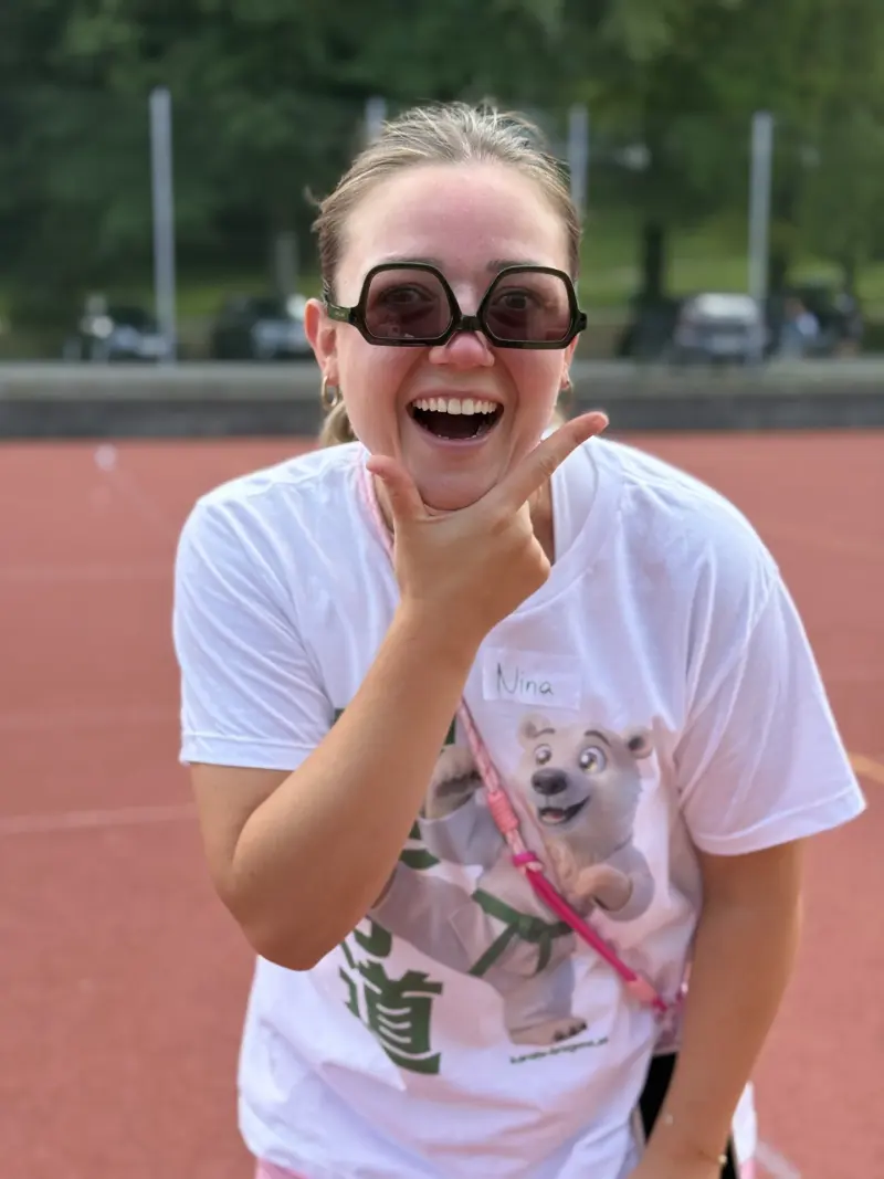 Frau lacht mit Sonnenbrille und erhobener Hand